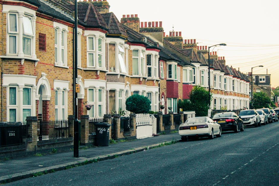 A row of terraced Victorian-style houses on a residential street in Tottenham Green, London, with brick façades, white window frames, and pitched tiled roofs topped with multiple chimney stacks. The
